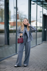 a lady in a black top, a grey alpaca wool jacket and a pair of grey pants